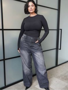 Woman with short black hair wearing a black long-sleeve shirt and wide-leg jeans