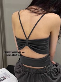 Woman with dark hair wearing a dark strappy ruched top, seen from behind