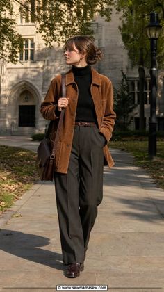 Woman in a corduroy jacket and wide-leg pants walking on a college campus