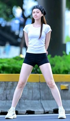 Woman in a white t-shirt and black shorts with a bandana on her head outdoors