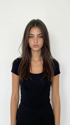 Woman with long dark hair wearing a black shirt against a white background