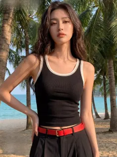 Woman with long hair wearing a black tank top and red belt on a beach