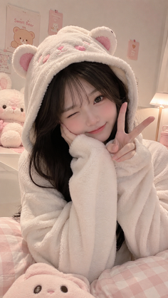 Woman in a white bear hoodie winking and making a peace sign