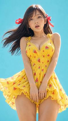 Woman in a yellow watermelon print dress with red ribbons in her hair