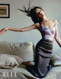 Woman with long hair in a satin dress posing on a couch with motion blur