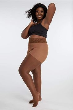 Woman in a black top and tights with lace trim posing in a studio
