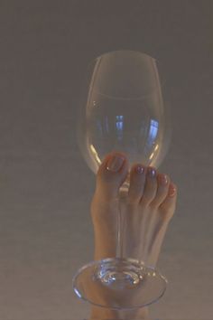 A foot holding a wine glass with clear nail polish
