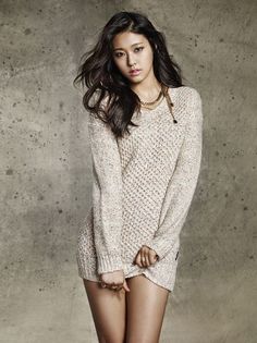 Woman in an oversized sweater and jewelry posing in a studio
