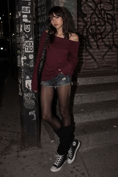 Woman in an off-shoulder top and denim shorts with tights at night