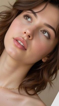 Close up of a woman with brown hair and a gold necklace looking up