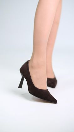 Woman's legs in brown pointed-toe high heels against a white background