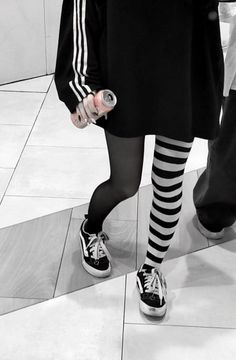 Person in an oversized shirt and striped socks holding a can