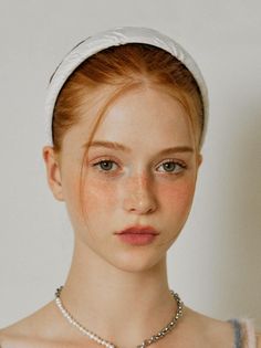 Close-up portrait of a woman with red hair, green eyes, and freckles