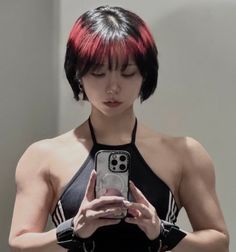 Woman with short hair and red highlights taking a mirror selfie