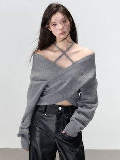 Woman with long hair wearing a gray off-shoulder sweater and black leather pants