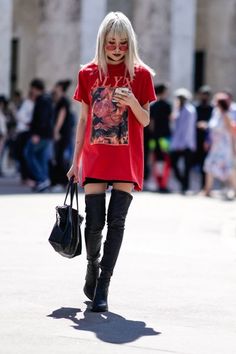 Woman with blonde hair wearing a red t-shirt and thigh-high boots outdoors