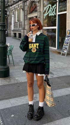 Woman with short red hair in a striped shirt and pleated skirt on a city street