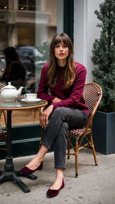Woman with long hair and bangs sitting at an outdoor cafe table