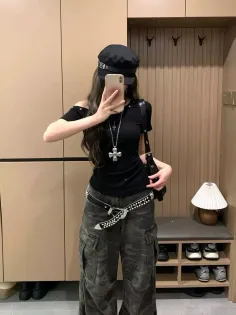 Person in a black hat and cargo pants taking a mirror selfie indoors