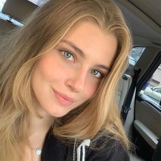 Young woman with blonde hair and blue eyes in a black hoodie inside a car