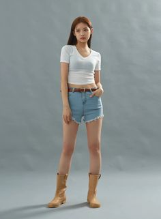 Woman in a white crop top and denim shorts with cowboy boots in a studio