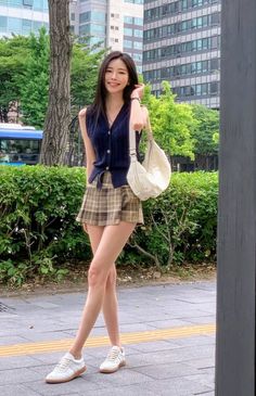Woman in a plaid skirt and sleeveless top posing outdoors