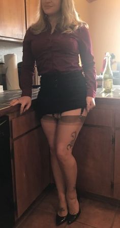 Woman in a black skirt and stockings with a garter belt in an indoor setting