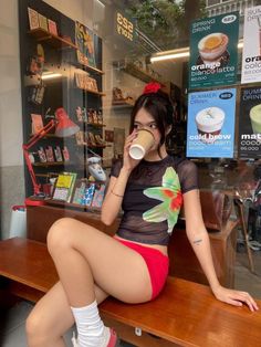 Woman in a sheer top and red shorts drinking coffee in a cafe