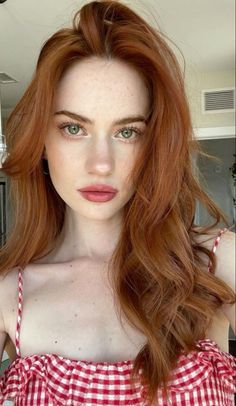 Woman with red hair and green eyes wearing a red and white gingham top