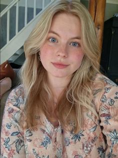 Blonde woman with blue eyes and freckles wearing a floral shirt indoors