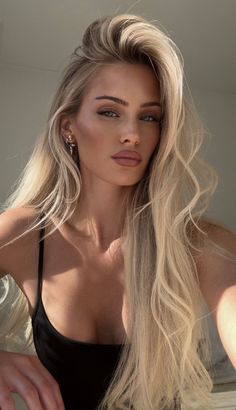 Woman with long blonde hair wearing a black top, looking directly at the camera