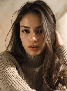 Woman with long brown hair wearing a turtleneck sweater, with soft lighting on her face
