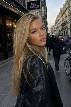 Woman with long blonde hair and a black leather jacket on a city street