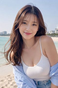 Woman with long hair in a white tank top and blue shirt at the beach