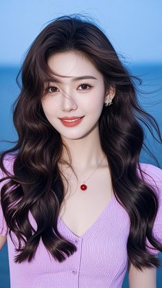 Woman with long wavy hair wearing a purple top and red necklace outdoors