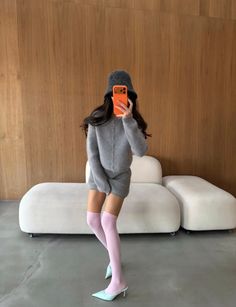 Person in a gray sweater and pink thigh-high socks taking a mirror selfie