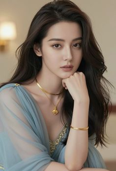 Woman with long dark hair wearing a blue dress and gold jewelry