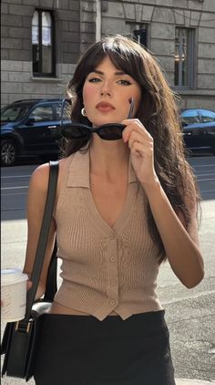 Woman with long hair holding sunglasses on a sunny street