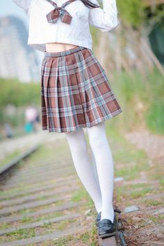 Person in a school uniform with a plaid skirt and white stockings outdoors