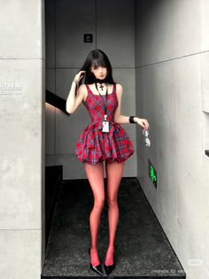 Anime style girl in a red plaid dress and red tights standing indoors