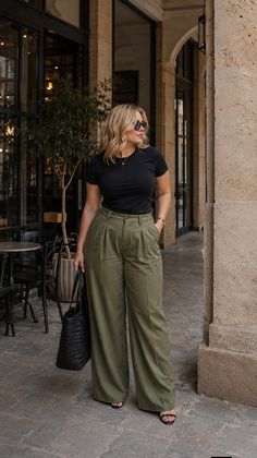 Woman with blonde hair and sunglasses wearing a black t-shirt and wide leg pants outdoors