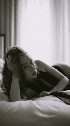 Woman with curly hair lying on a bed in black and white