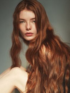 Woman with long red hair and exposed skin looking directly at the viewer