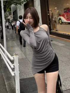 Woman in a gray top and black shorts posing on a city street