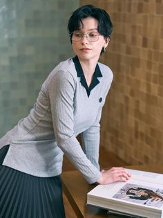 Woman with short hair and glasses leaning on a table with an open book