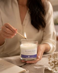 Person lighting a lavender scented candle with a matchstick