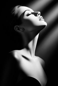 Black and white portrait of a woman with dramatic lighting on her face and upper body