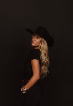 Woman with long blonde hair and a cowboy hat looking over her shoulder
