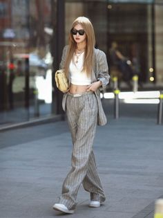Woman in a pinstripe suit and crop top walking outdoors