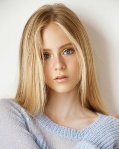 Young woman with blonde hair and blue eyes wearing a light blue sweater
